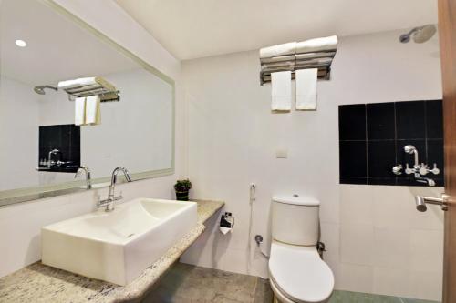 a bathroom with a sink and a toilet and a mirror at Manpho Bell Hotel & Convention Center in Bangalore