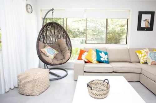 a living room with a hanging chair and a couch at Kookaburras at South Golden - 9min walk to idyllic beach in South Golden Beach