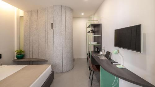 een slaapkamer met een bed en een bureau met een televisie bij La Memoria Hotel - City Centre in Ho Chi Minh-stad