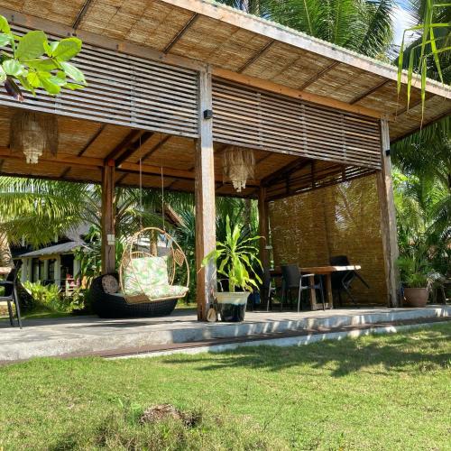 a wooden pavilion with a table and chairs in a yard at Sandy Feet Siargao in General Luna