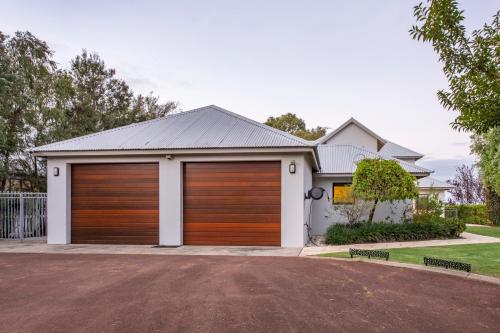 a house with wooden garage doors on a driveway at The Beach Club in Vasse