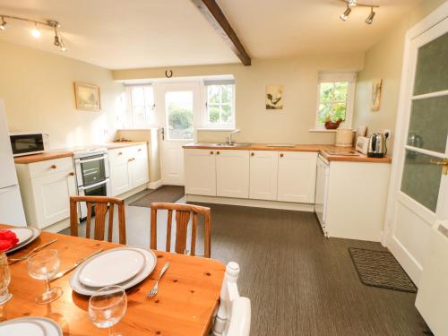 a kitchen with a wooden table and a kitchen with white cabinets at Coverdale Cottage in Carlton