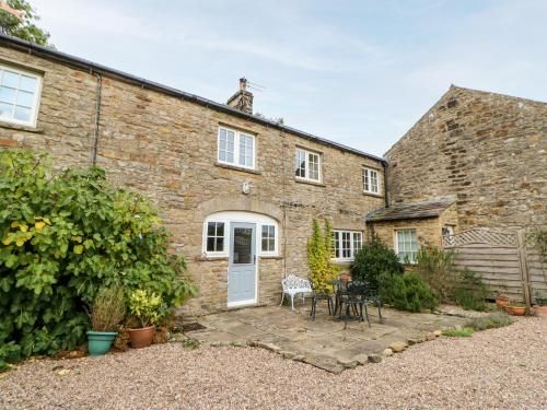 a brick house with a white door and a patio at Coverdale Cottage in Carlton