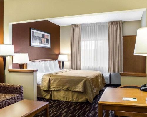 a hotel room with a bed and a table at Quality Suites Near West Acres in Fargo