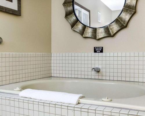 a bathroom with a bath tub with a mirror at Quality Suites Near West Acres in Fargo