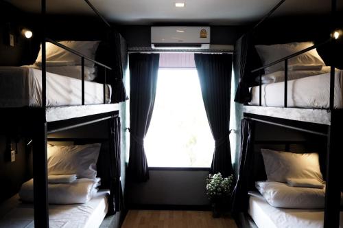 a room with three bunk beds with a window at La Malila Hostel in Udon Thani