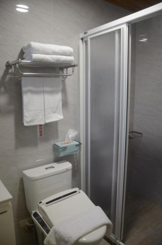 a bathroom with a shower and a toilet and towels at Rebecca Hostel in Chaozhou