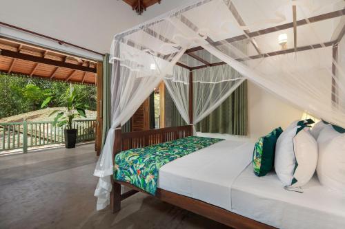 a bedroom with a canopy bed and a balcony at Green Escape Unawatuna in Unawatuna