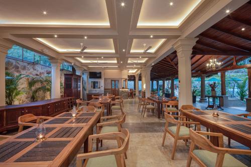un restaurante con mesas y sillas de madera y ventanas en Green Escape Unawatuna, en Unawatuna
