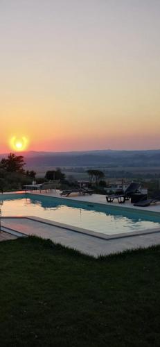 a large swimming pool with the sunset in the background at Tenuta Lisetta in Monterotondo