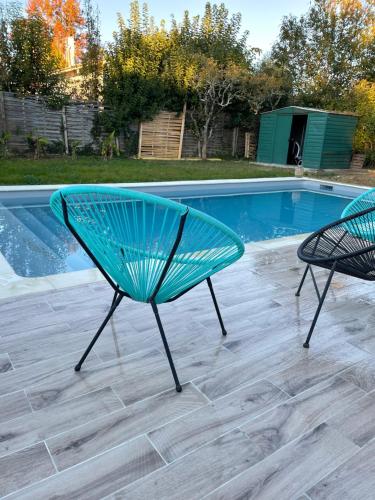 two green chairs sitting next to a swimming pool at Maison chaleureuse in Villeneuve-sur-Lot