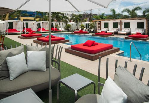 キングストンにあるS Hotel Kingstonの赤い枕とソファ付きのプールがスイミングプールの隣にあります。