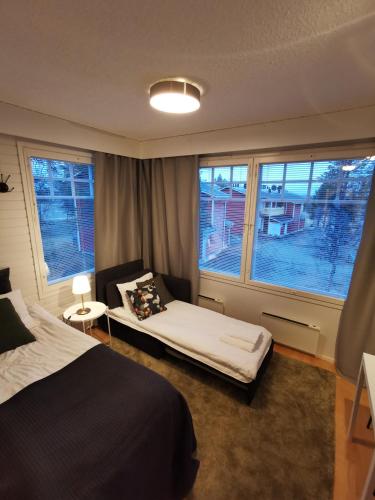 ein Schlafzimmer mit einem Bett, zwei Fenstern und einem Sofa in der Unterkunft Luulampi - Studio in the center of Saariselkä in Saariselkä