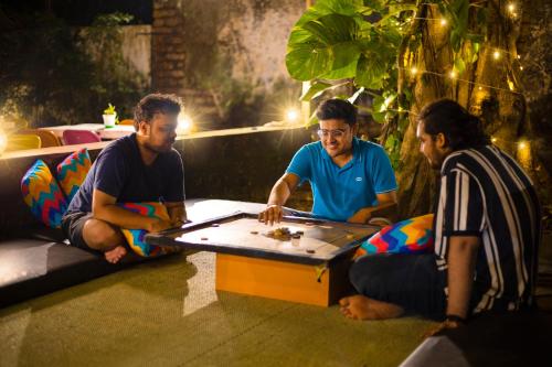 a group of three men playing a game with a table at goSTOPS Lite Alleppey in Alleppey
