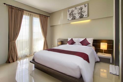 a bedroom with a large bed and a window at ABISHA Resort Jimbaran in Jimbaran
