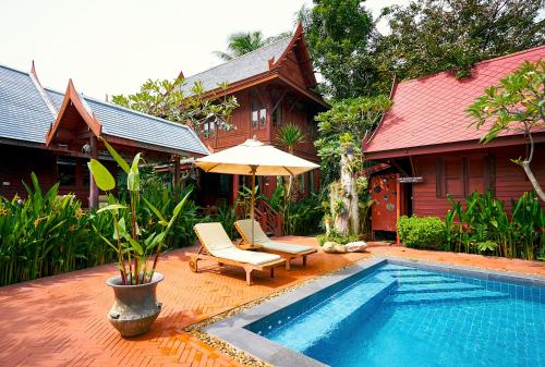 a patio area with a pool, chairs, and a lawn chair at Ruenkanok Thaihouse Resort in Hua Hin