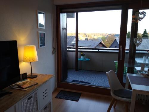 ein Wohnzimmer mit einem großen Fenster und einem Schreibtisch mit einer Lampe in der Unterkunft Apartment 365 mit Sauna, Schwimmbad und Fitness in Schönwald