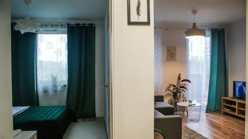 uma sala de estar com cortinas verdes e um quarto com um sofá em 5 min od Dworca PKP Apartament em Lublin