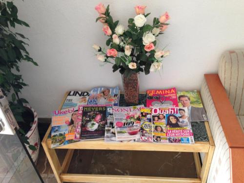 a table with magazines and a vase with flowers at Hostal de la Caravel-la in Cala d´Or