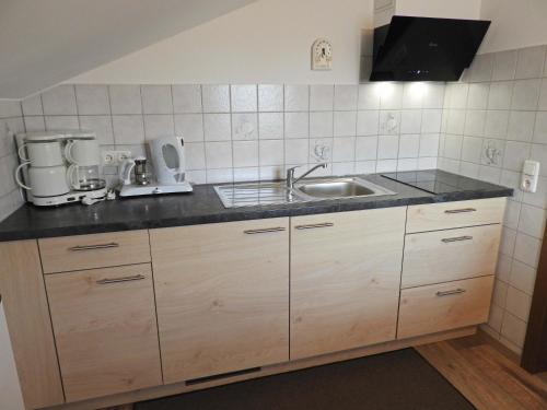 eine Küche mit Holzschränken und einem Waschbecken in der Unterkunft Appartements Hirsch in Bad Birnbach