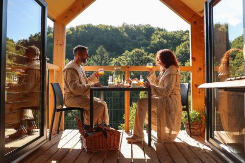 a man and woman sitting at a table on a deck with drinks at Nesting resort Posestvo SONČNI RAJ in Maribor
