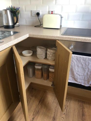 a kitchen counter with a cupboard with dishes at Central Lisburn Duplex Apartment No Parties in Lisburn