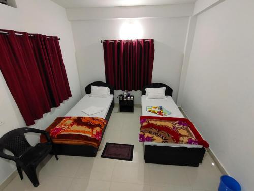 a room with two beds and red curtains at Gaurav guest house in Bodh Gaya