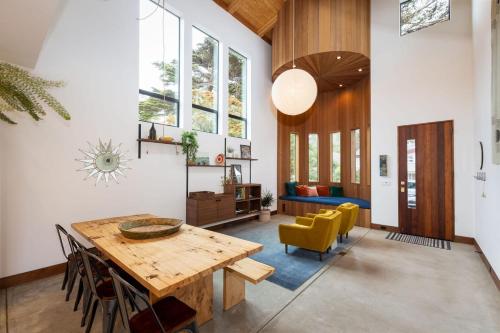 ein Wohnzimmer mit einem Holztisch und gelben Stühlen in der Unterkunft Modern indoor-outdoor living wHot Tub Walk to Beaches & Mountain Trails in Montara