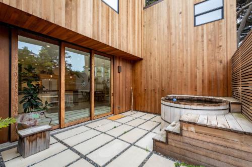 een houten huis met een jacuzzi op een patio bij Modern indoor-outdoor living wHot Tub Walk to Beaches & Mountain Trails in Montara