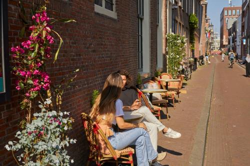 
a woman sitting on a bench in front of a brick building at Hôtel Frenchie in Haarlem
