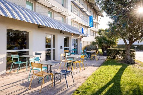 un groupe de tables et de chaises devant un bâtiment dans l'établissement ibis budget Carcassonne Aéroport - A61, à Carcassonne