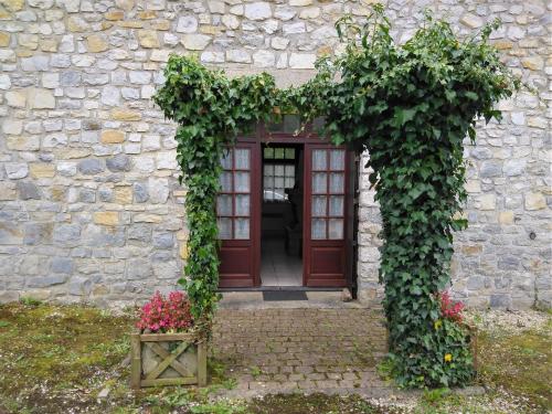 an entrance to a stone building with a red door at Gîtes Les Clairets - Normandie in Mortain