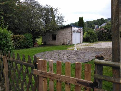 a wooden fence in front of a yard with a building at Gîtes Les Clairets - Normandie in Mortain