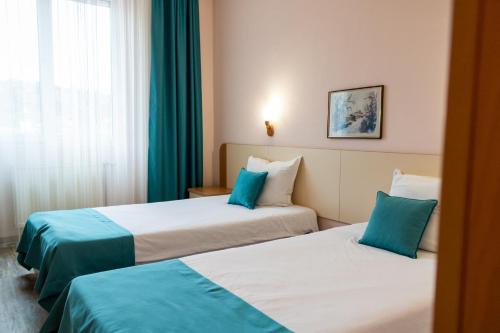 Dos camas en una habitación de hotel con azul y blanco en Hotel Balkan en Gabrovo