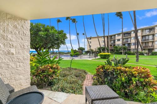 a patio with chairs and a park with palm trees at Kanai A Nalu Resort 114 in Wailuku