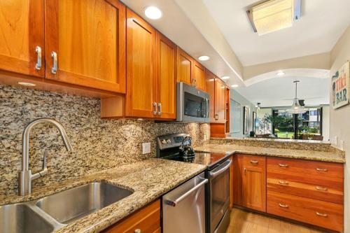 a kitchen with wooden cabinets and stainless steel appliances at Kanai A Nalu Resort 114 in Wailuku
