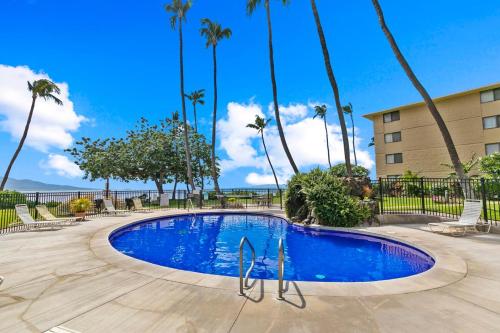 a swimming pool at a resort with palm trees at Kanai A Nalu Resort 114 in Wailuku