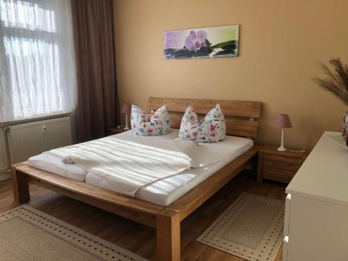 um quarto com uma cama com lençóis brancos e almofadas em Ferienwohnungen Heideblick em Gräfenhainichen