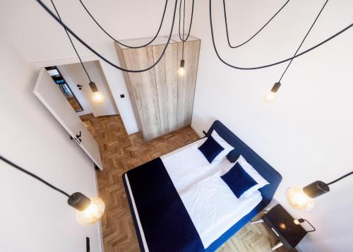 a bedroom with a bed with blue pillows and lights at Apartament Matejki E in Bielsko-Biała