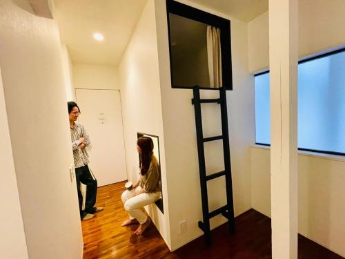 a man and woman standing in a room with a mirror at En- Hostel & Café bar in Amami