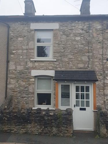 a stone house with a white door and two windows at Emelia Cottage Ingleton in Ingleton 