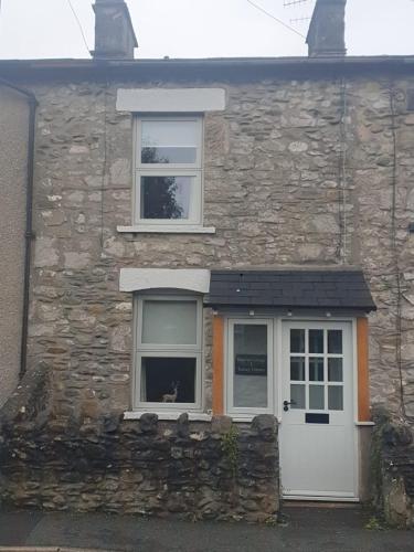 a stone house with a white door and two windows at Emelia Cottage Ingleton in Ingleton