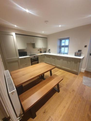 a kitchen with a wooden table and a bench at Emelia Cottage Ingleton in Ingleton