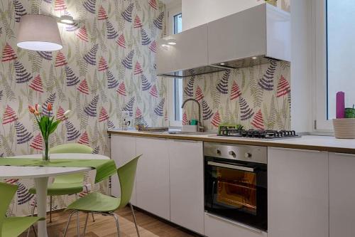 uma cozinha com um fogão e uma mesa com cadeiras verdes em PrimoPiano - Ariberto em Milão