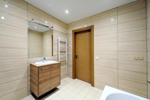 een badkamer met een wastafel, een douche en een spiegel bij Valensia Apartment in Druskininkai