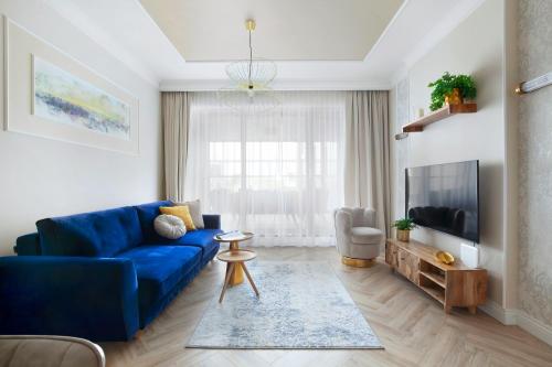 a living room with a blue couch and a tv at Elite Apartments Granaria The View in Gdańsk