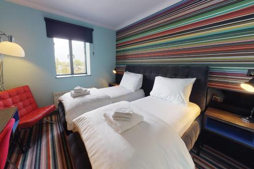 ein Hotelzimmer mit 2 Betten und einem roten Stuhl in der Unterkunft Village Hotel Birmingham Walsall in Walsall