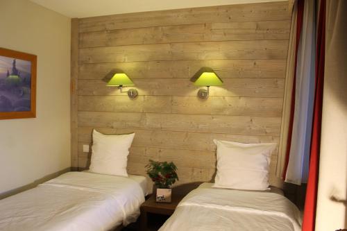 2 Betten in einem Zimmer mit 2 Lampen an der Wand in der Unterkunft Résidence Christiana 406 Clés Blanches Courchevel in La Tania