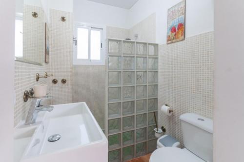 a white bathroom with a sink and a toilet at Palomas in Denia