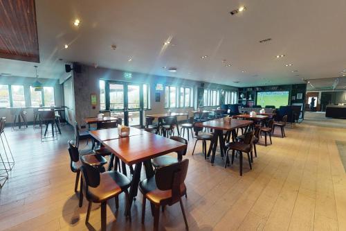 a restaurant with wooden tables and chairs in a room at Village Hotel Birmingham Dudley in Dudley